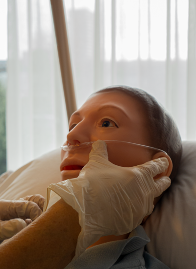 Een deelnemer brengt een zuurstof neusbril aan bij een patiënt om deze vrh te laten aftoetsen 